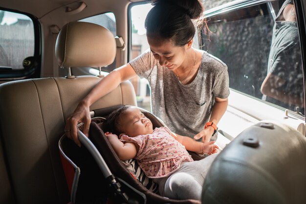 Asiatische Mutter, die Babystuhl befestigt