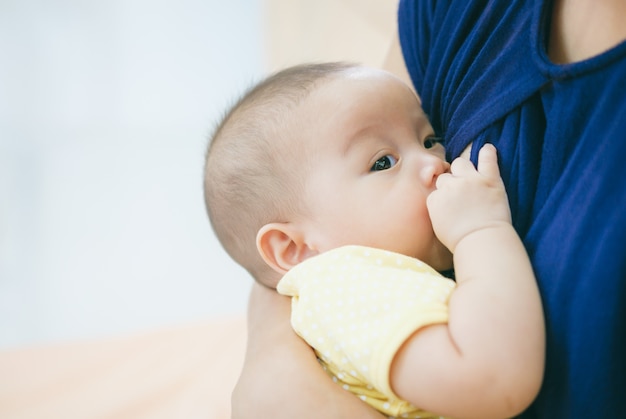 Asiatische Mutter, die ihr Baby hält und stillt