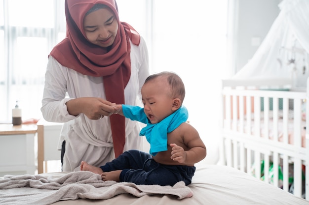 Asiatische Mutter, die ihre Babykleidung wechselt