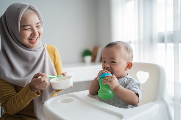 Asiatische Mutter füttert ihren kleinen Sohn mit Löffel