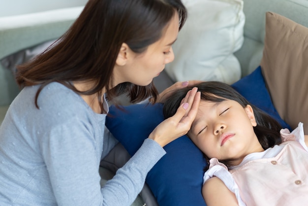 Asiatische Mutter kümmert sich um ihr Kind, das zu Hause Fieber und Krankheit bekam.