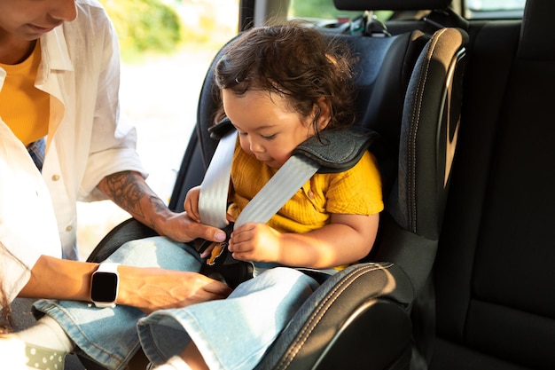 Asiatische Mutter sitzt mit einem Kleinkind in einem Baby-Autositz