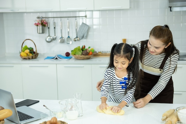 Asiatische Mutter und Kind kochen aus Mehl in der Küche, Freizeitbeschäftigung zu Hause.