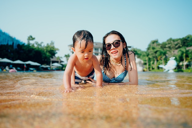 Foto asiatische mutter und kleiner sohn genießen das schwimmen in einem schwimmbad in den sommerferien.