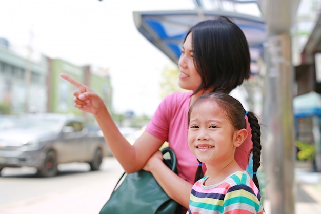 Asiatische Mutter und Tochter auf Bus der öffentlichen Transportmittel etwas auf das Kindermädchenschauen zeigend.