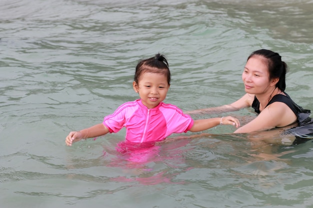 Asiatische Mutter und Tochter, die Spaß hat, wäscht auf Meer