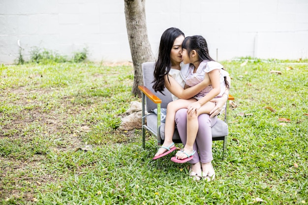 Asiatische Mutter und Tochter machen zu Hause lustige Aktivitäten auf der Wiese im Garten. Glückliches liebevolles Familienkonzept.