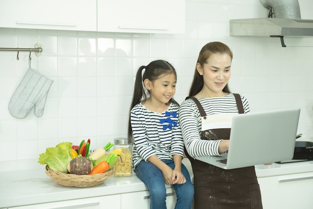 Asiatische Mutter und Tochter mit Laptop in der häuslichen Küche