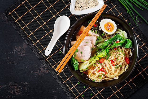 Asiatische Nudeln Miso Ramen mit Ei, Schweinefleisch und Pak Choi Kohl in der Schüssel. Japanische Küche. Ansicht von oben. Flach liegen