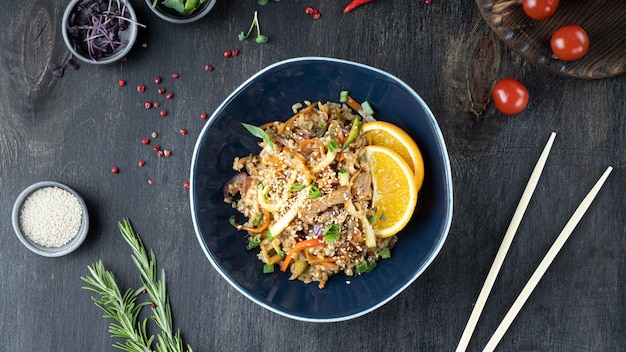 Asiatische Nudeln Yakisoba mit Schweinefleisch in einer Schüssel auf dunkler Holztischplatte