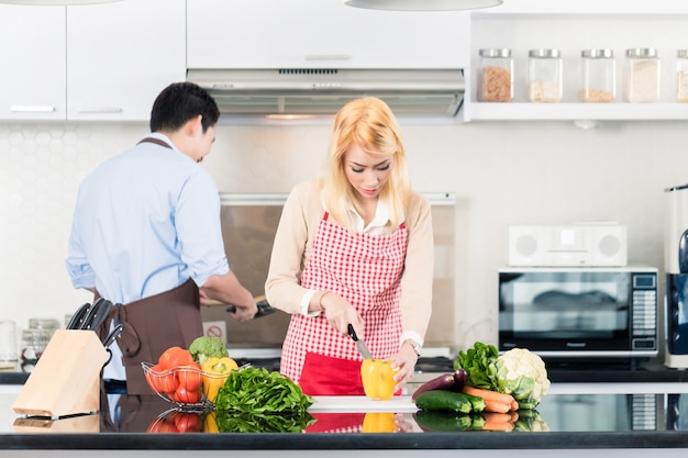 Asiatische Paare, die in der stilvollen und modernen Küche kochen