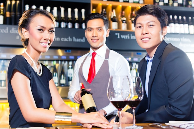 Asiatische Paare, die Rotwein in der Bar schmecken