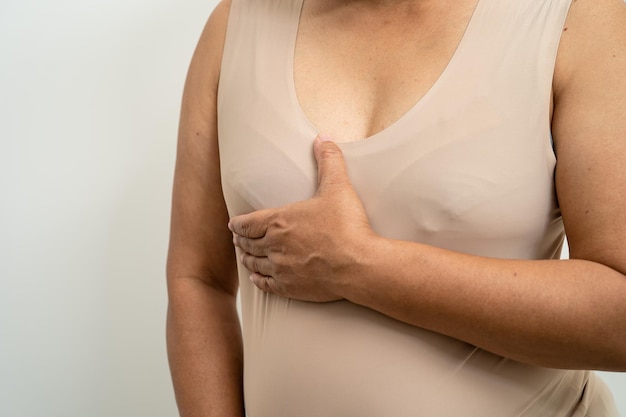 Foto asiatische patientin, die ihre brust überprüft und sich sorgen macht selbstuntersuchung der brust oder bes-symbol des weltbrustkrebstages