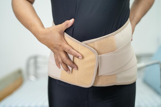Asiatische Patientin mit Rückenschmerzen-Stützgürtel für orthopädische Lendenwirbelsäule