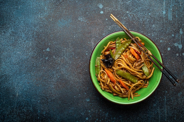 Asiatische Pfannennudeln mit Huhn und Gemüse in Draufsicht der grünen Schüssel