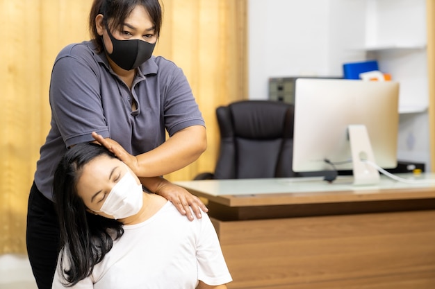 Asiatische Quarantänefrau massieren zu Hause mit Gesichtsmaske