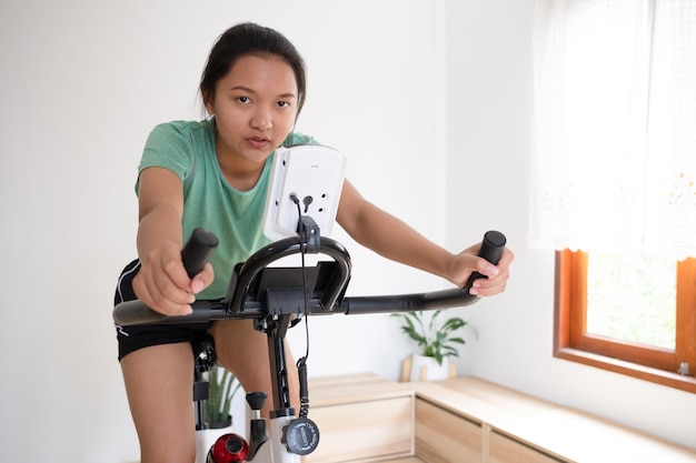 Asiatische Radfahrerin Sie trainiert zu Hause im Wohnzimmer