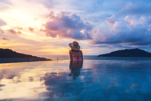 Asiatische reisebikinifrau entspannen im überlaufpool im resort phuket beach thailand