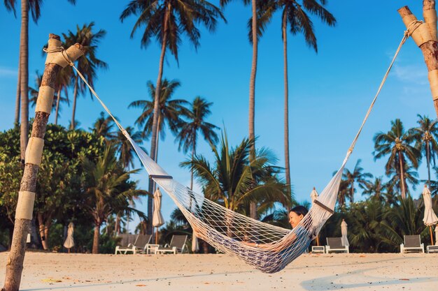 Foto asiatische reisende frau, die auf der hängematte am strand liegt