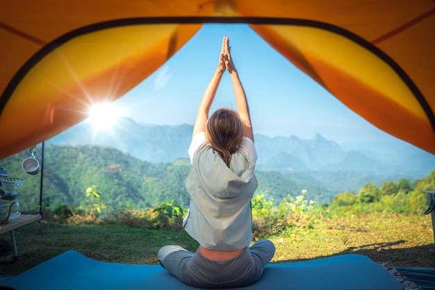 Asiatische Reisende machen Yoga im Zelt auf ihrem Campingplatz mit Berg- und Outdoor-Hintergrund Thailand