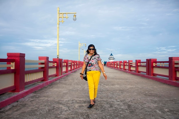 Asiatische reisende thailändische alte frauen der 60er reisen besuchen und posieren porträt für ein foto auf dem gehweg der roten brücke saphan saranwithi am prachuap bay beach in prachuap khiri khan thailand