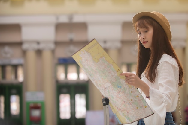Asiatische Reisendfrau, die Karte Bahnstation betrachtet