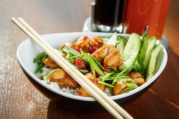 Asiatische RiÃÂƒÃ'Â'ÃƒÂ'Ã'Â e mit Hühnchen und Gemüse in ovaler Platte mit Bambusstäbchen auf einem Holztisch im asiatischen Restaurant