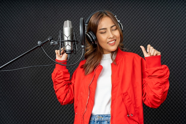Asiatische Sängerin in einem Aufnahmestudio unter Verwendung eines Studiomikrofons