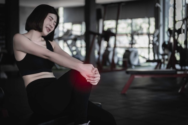 Asiatische schlanke Frau spielt Fitness im Fitnessstudio. Sie hat Schmerzen vom Training