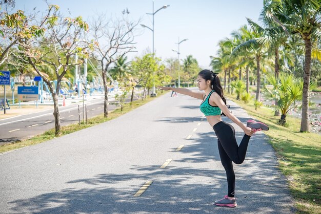 Asiatische schlanke Frau wärmt sich vor der Arbeit aufslim Mädchen Übung fürs LebenThailänderDehnung des Körpers vor dem Joggen