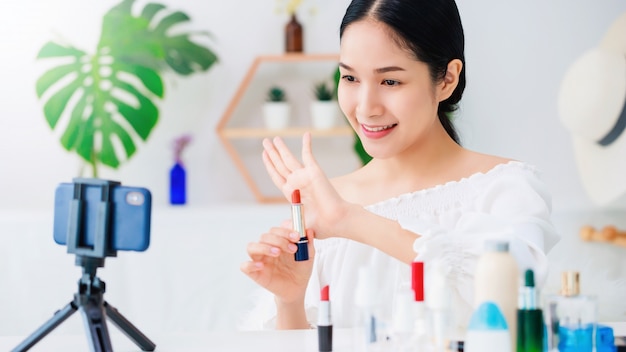 Asiatische schöne Frau, die Make-up-Produkte zeigt