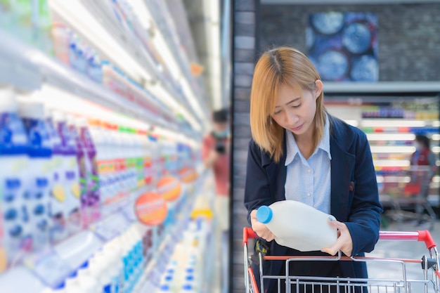 Asiatische schöne Frau kauft mit Einkaufswagen im Supermarkt ein