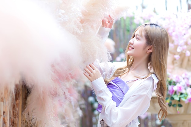 Foto asiatische schöne frau mit langen bronzenen haaren, die einen kurzen rock und weiße lange ärmel trägt