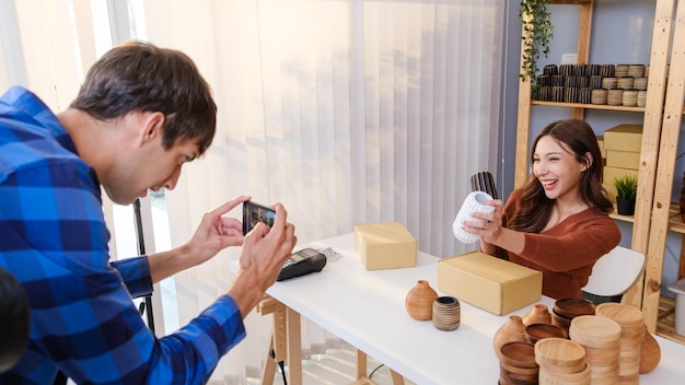 Asiatische schöne Frau verkauft Vase Produkt online Live-Streaming von kaukasischen Mann zu Hause Junge attraktive Mädchen verwenden Smartphone, das dem Kunden Waren zeigt und Details präsentiert Online-Shopping-Konzept