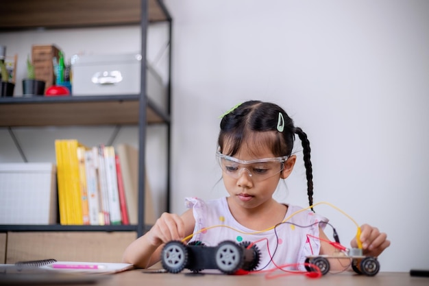 Asiatische Schüler lernen zu Hause, indem sie Roboterautos und elektronische Platinenkabel in MINT-STEAM-Mathematik-Ingenieurwissenschaften-Technologie-Computercode in Robotik für Kinderkonzepte codieren