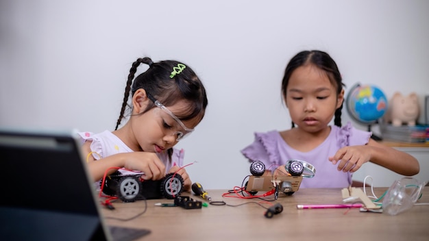 Asiatische Schüler lernen zu Hause, indem sie Roboterautos und elektronische Platinenkabel in MINT-STEAM-Mathematik-Ingenieurwissenschaften-Technologie-Computercode in Robotik für Kinderkonzepte codieren