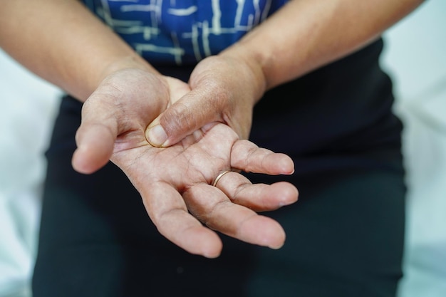 Asiatische Seniorin schmerzt ihre Hand und Finger Sehnenscheidenentzündung von De Quervain