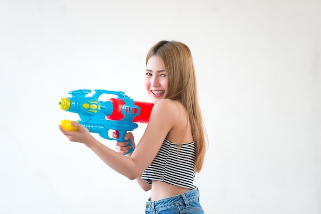 Asiatische sexy Frau mit Pistolenwasser in der Hand auf weißem HintergrundFestival Songkran Tag in ThailandDas beste Festival von ThailandLand des Lächelns