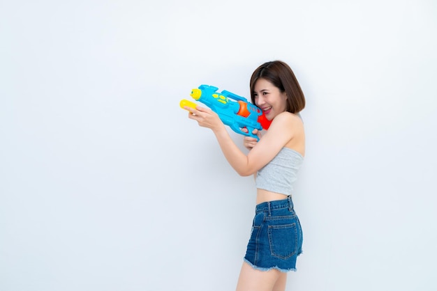 Asiatische sexy Frau mit Pistolenwasser in der Hand auf weißem HintergrundFestival Songkran Tag in ThailandDas beste Festival von ThailandLand des Lächelns