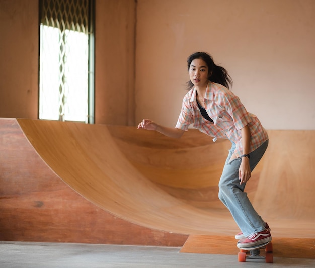 Asiatische Skaterin macht Tricks beim Springen in der Tiefgarage Urban Activity Indoor Lifestyle