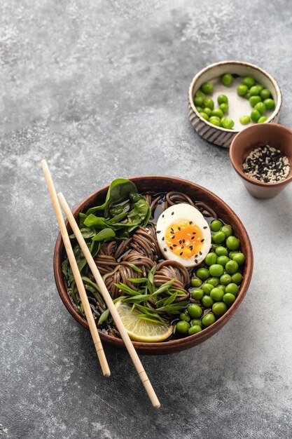 Foto asiatische soba-nudelsuppe mit gekochtem hühnerei, sesamsamen, grünen erbsen und frühlingszwiebeln