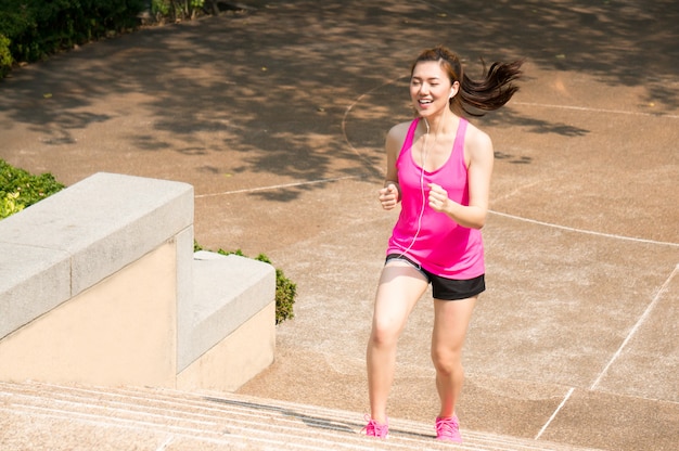 Asiatische Sportfrau, die, laufend in Park rüttelt