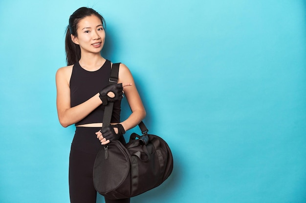 Asiatische Sportlerin mit Fitness-Rucksack im Studio.