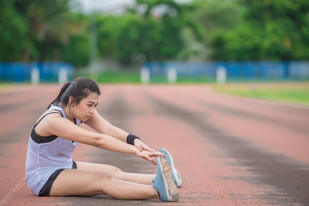 Asiatische sportliche Frau, die den Körper dehnt und frische Luft im Park atmetThailänderFitness- und BewegungskonzeptJoggen auf der Strecke