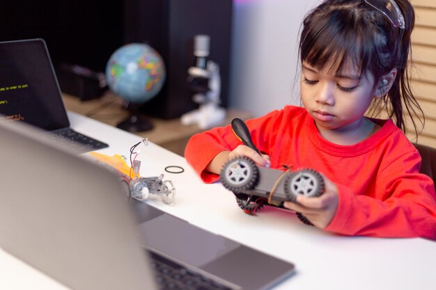 Asiatische Studenten lernen zu Hause in der Codierung von Roboterautos und elektronischen Platinenkabeln im MINT-DAMPF-Mathematik-Ingenieurwissenschaften-Technologie-Computercode im Robotik-Konzept für Kinder
