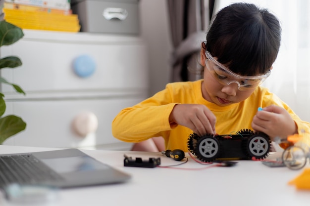 Asiatische Studenten lernen zu Hause in der Codierung von Roboterautos und elektronischen Platinenkabeln im MINT-DAMPF-Mathematik-Ingenieurwissenschaften-Technologie-Computercode im Robotik-Konzept für Kinder