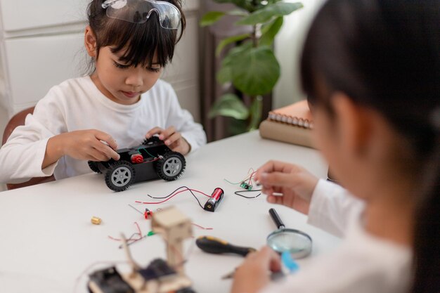 Asiatische Studenten lernen zu Hause in der Codierung von Roboterautos und elektronischen Platinenkabeln im MINT-DAMPF-Mathematik-Ingenieurwissenschaften-Technologie-Computercode im Robotik-Konzept für Kinder