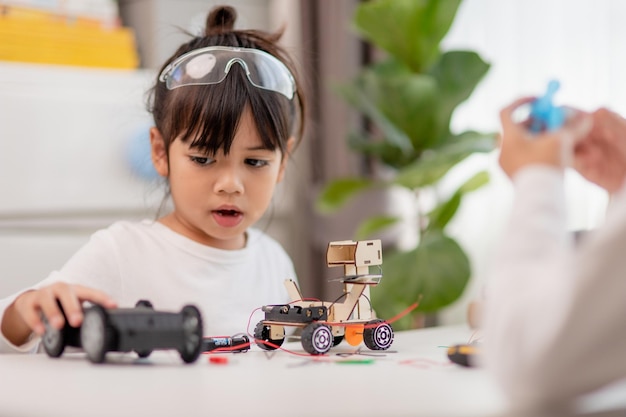 Asiatische Studenten lernen zu Hause in der Codierung von Roboterautos und elektronischen Platinenkabeln im MINT-DAMPF-Mathematik-Ingenieurwissenschaften-Technologie-Computercode im Robotik-Konzept für Kinder