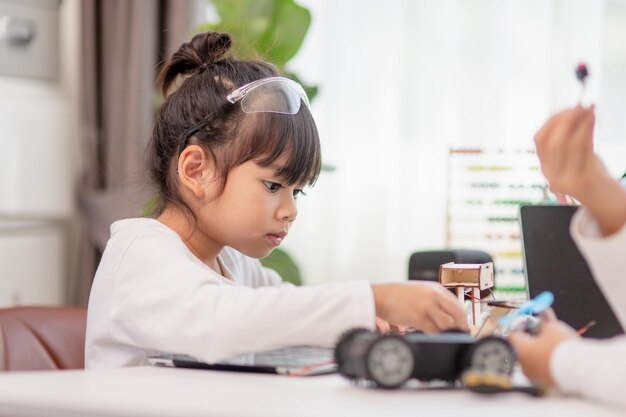 Asiatische Studenten lernen zu Hause in der Codierung von Roboterautos und elektronischen Platinenkabeln im MINT-DAMPF-Mathematik-Ingenieurwissenschaften-Technologie-Computercode im Robotik-Konzept für Kinder