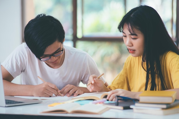 Asiatische Studenten lesen Bücher und studieren gemeinsam Nachhilfe